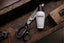 Tabac Original Mild After Shave Fluid liegt auf Holztisch neben Schere und Lochzange.